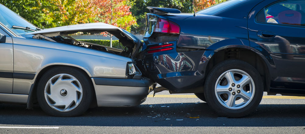Two cars involved in a rear end collision damaging both vehicles.