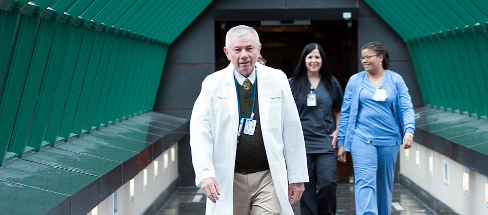 a doctor and two nurses or other medical staff are walking through an above ground crosswalk.